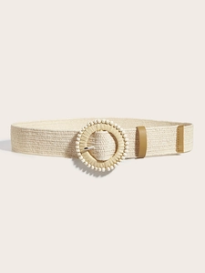 Dettaglio di una cintura intrecciata beige con fibbia rotonda e perline decorative