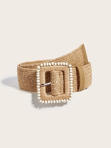 Dettaglio della cintura intrecciata in paglia beige con fibbia quadrata e inserti in perline