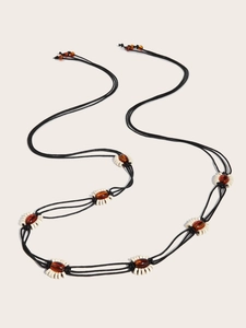 Détail d'une ceinture tressée bohème Y2K avec perles d'ambre et anneaux sur cordon noir