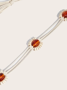 Détail d'une ceinture boho tissée avec perles d'ambre et disques de bois sur corde en coton