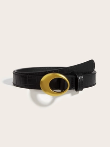 Detail of black faux leather belt with crocodile texture and gold oval buckle on a table