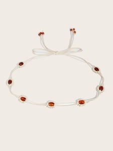 Détail d'une chaîne de taille bohème tressée crème avec perles d'ambre et glands