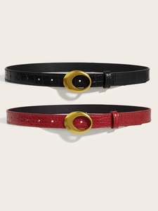 Detail of black and burgundy crocodile pattern belts with oval golden metal buckles