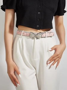 Close-up of pink glitter belt with silver butterfly buckle on white high-waist pants