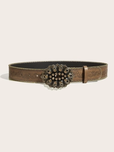 Detail of a brown leather belt with embossed floral patterns and amber crystal buckle