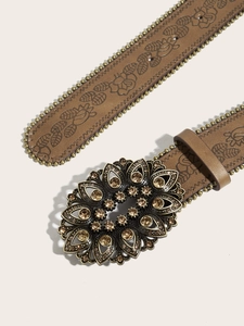 Detail of vintage brown leather belt with embossed floral pattern and studded buckle
