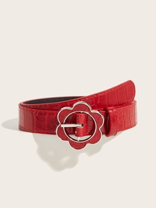 Detail of red crocodile textured leather belt with a vintage silver floral metal buckle
