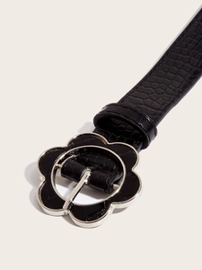 Detail of black crocodile texture belt with silver floral buckle and embossed leather strap
