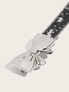 Macro view of silver butterfly buckle on black sequined canvas belt with metallic beads