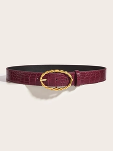 Detailed macro view of burgundy faux crocodile belt with twisted gold metal buckle