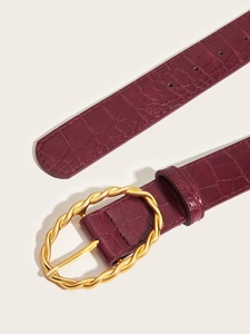 Close-up of burgundy crocodile pattern leather belt with golden textured buckle