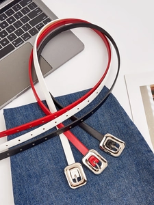 Détail de ceintures fines en cuir noir, rouge et blanc avec boucles en métal argenté