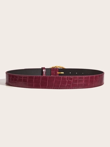 Macro detail of wine red crocodile embossed leather belt with golden woven buckle
