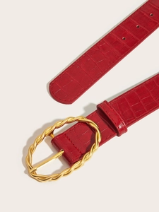 Close-up of red crocodile embossed leather belt with luxury golden twisted oval buckle