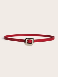 Détail d'une fine ceinture rouge avec une boucle rectangulaire en métal argenté