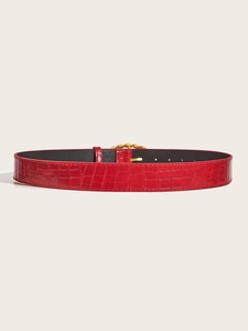 Detailed macro view of red crocodile embossed leather belt with gold metal pin buckle