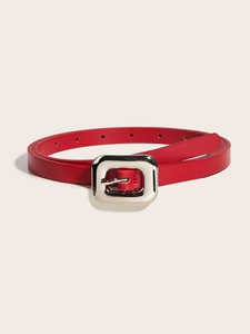 Détail d'une fine ceinture en cuir rouge avec une boucle carrée en métal argenté
