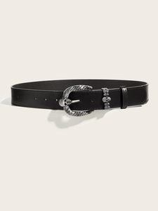 Close-up of a punk style black leather belt with a silver skull buckle and relief details