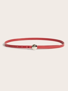 Detail of red leather skinny belt with a polished silver circular metal buckle