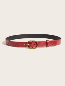 Detail of red faux leather belt with crocodile pattern and oval vintage gold buckle