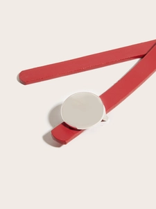 Close-up of a minimalist round silver metal buckle on elegant red display props