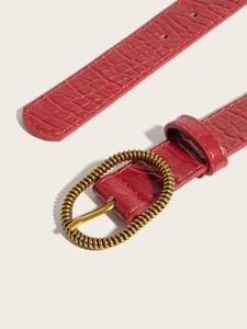 Detail of red crocodile texture belt with vintage gold oval spiral buckle for jeans