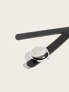 Close-up of black leather belt detail featuring a polished silver round metal buckle