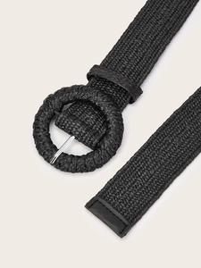 Detail of black woven belt with large round buckle and high quality leather wrapped end