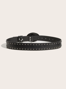 Detail of black punk belt featuring silver metal studs and large vintage embossed round buckle