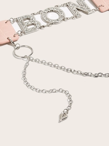 Macro detail of pink crocodile texture leather belt with rhinestone letters and heart pendant