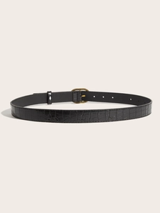 Detail of black crocodile texture belt with vintage bronze oval buckle on beige background