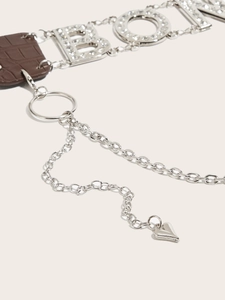 Detail of silver belt chain with rhinestone lettering and brown faux crocodile leather