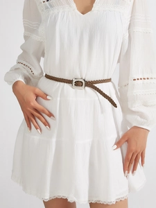 Détail d'une fine ceinture tressée marron avec boucle argentée sur robe en dentelle