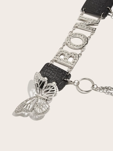 Detail of crocodile embossed leather belt with rhinestone letters and butterfly buckle
