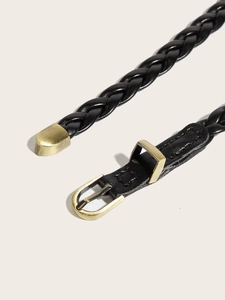 Detail of black woven leather belt featuring a vintage gold buckle and metal tip