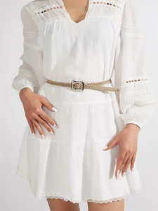 Détail d'une fine ceinture tressée kaki avec boucle carrée argentée sur robe
