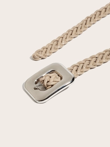 Détail macro de la texture de ceinture tressée beige avec boucle métallique argentée