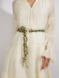 Detail der gewebten Leinen-Taillenkordel mit grünen Blättern auf weißem Rüschenkleid