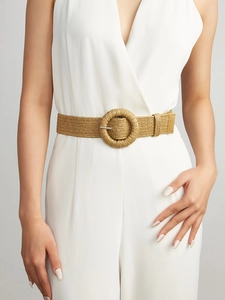Close-up of a woven straw belt with a round buckle on a white dress for a vintage look