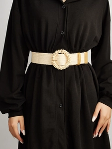 Close-up of woven stretch belt for women with beige beaded round buckle on black dress