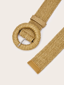 Detail of khaki woven belt with a large round buckle and a refined leather end finish