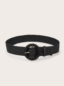 Detail of black woven belt featuring a round buckle embellished with glossy beads