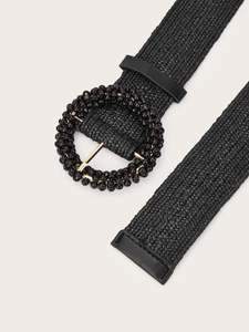 Detail of woven black waist belt featuring a beaded round buckle and leather reinforced ends