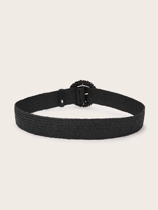 Close-up of black woven belt with circular beaded buckle and detailed fiber texture