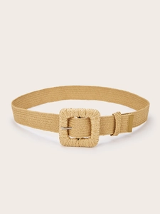 Close-up of bohemian woven straw belt with a large square buckle and faux leather tip