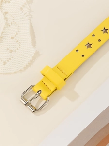 Detailed close-up of yellow skinny star belt with silver pin buckle and star cutouts