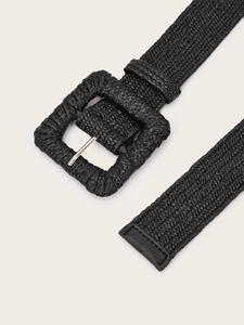 Detail of black woven belt featuring a square wrapped buckle and textured straw pattern