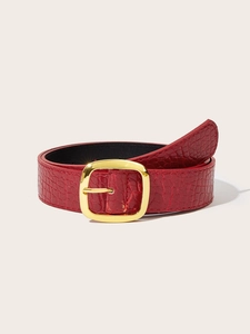 Detail of red faux crocodile leather belt with metallic gold buckle on white background