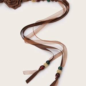 Cintura etnica intrecciata con fiore di stoffa e perline su sfondo bianco puro