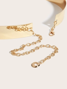Détail de la large ceinture en métal doré brillant avec chaîne à anneaux réglable